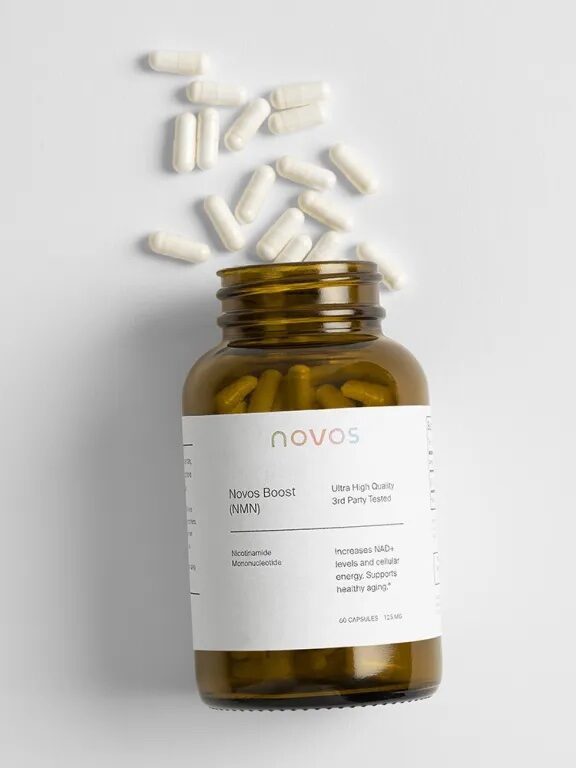 Brown bottle labeled "Novos Boost" with white capsules scattered around it on a white surface.